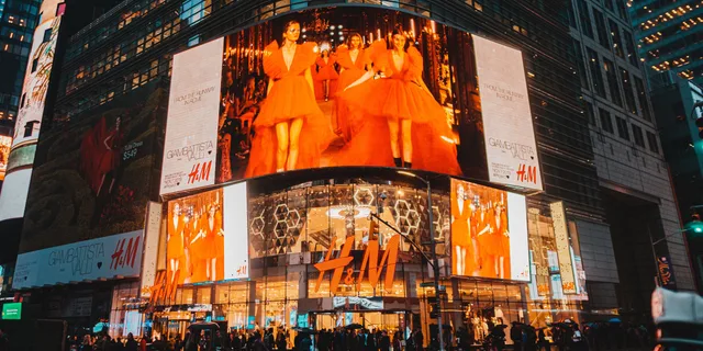 Times Square in NYC illuminated by H&M billboards, capturing urban nightlife and energy. Retail media review methodology: freeze the subject, classify four evidence types, label paid content